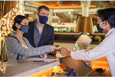Mitarbeiter an der Rezeption im Hotel, der medizinische Maske  trägt.