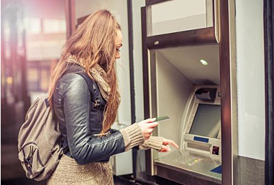 Junge Frau, die Geld von der Kreditkarte am ATM abzieht